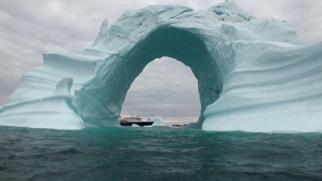 Iceberg arch like Darwin arch in Galapagos Islands. Fantastic wonderful amazing video grenland nature iceland. Lovely shooting the life of nature, seaside and mountains. Global warming.