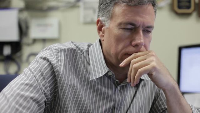 A pensive mature man sitting in his office at work.