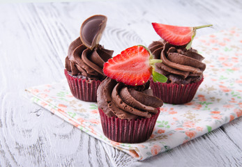 Chocolate cupcakes with strawberry and chocolate on a wooden table.