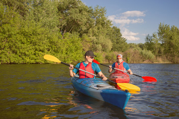 Men travel by canoe on the river in the summer a sunny day.