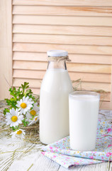 A bottle of rustic milk and glass of milk on a white wooden table