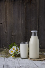 Glass of milk and bottle on wooden background 