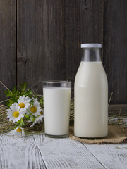A bottle of rustic milk and glass of milk on a wooden table