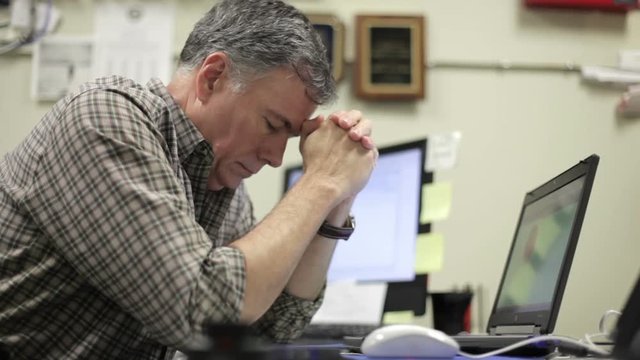 A mature businessman sitting and working on computer showing signs of worry or stress.
