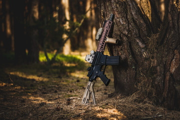 assault rifle leaning on a tree in the forest