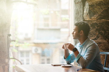Handsome Arabian guy is drinking hot beverage
