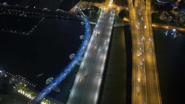 Cinemagraph of a magnificent aerial view of the Helix bridge and busy roads in Singapore at night. Time lapse sequence. Loopable motion background, only the ferry is moving. Traffic is frozen in time.