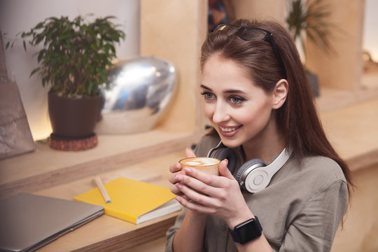 Cheerful young woman is drinking hot coffee