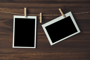 empty photo frames hanging with clothespins on wooden background