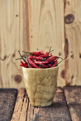 red peppers in a mug with wooden background, vintage style