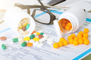 Doctor workplace. Pills, tablets, pen on patient history databas