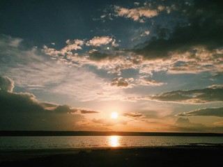 яркое сонце на синем небе с облаками садится за...
