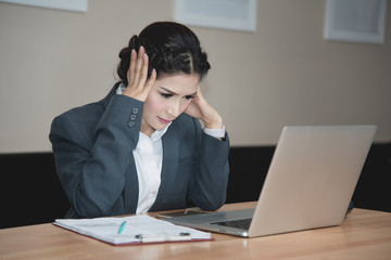 businesswoman working on laptop with headache having stress in t