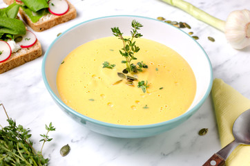 Pumpkin soup in a bowl with spoon on a marble