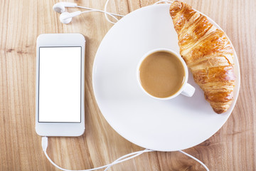 White smartphone, coffee and croissant