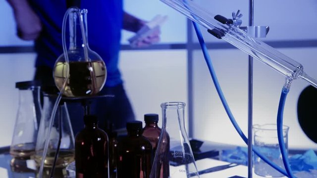 A man walks into the scene lays his pistol on a table filled with illegal drug paraphernalia and sits down.