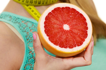 Woman measuring tape on neck holds grapefruit