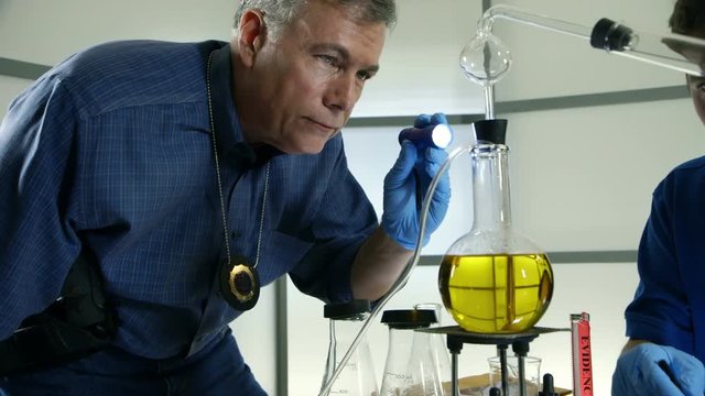 Two detectives or CSI agents talking while investigating a lab used for illegal drug manufacturing.