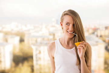 Smiling girl drinking from orange