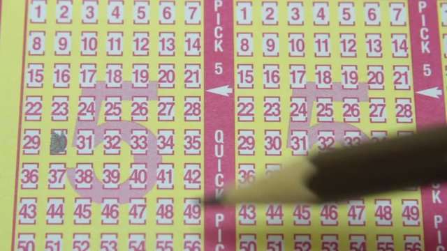 Pencil filling in numbered squares on lottery game piece.