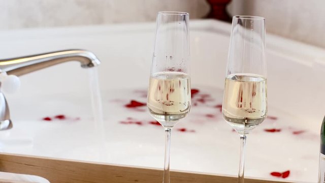 Rose Petals and Champagne Glasses Bath Tub Bubble Pull Focus. Celebrating Love, Wedding Honeymoon or Marriage Anniversary.
