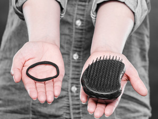 Female hands with comb and elastic hair.