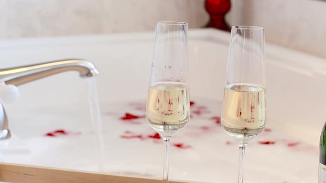 Rose Petals and Champagne Glasses Bath Tub Bubbles. Celebrating Love, Wedding Honeymoon or Marriage Anniversary.