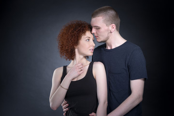 Portrait of a beautiful young couple in love posing at studio over dark background.