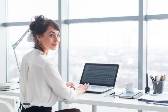 Attractive businesswoman working at office using pc, searching and studying business ideas on a laptop screen on-line.