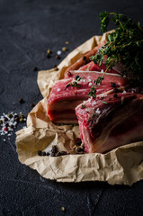 Raw bef ribs with thyme and spices on dark slate background. Selective focus