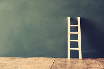 wooden ladder on blackboard background