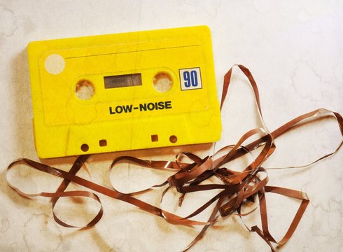 Vintage yellow musicassette with damaged tape. Selective focus.