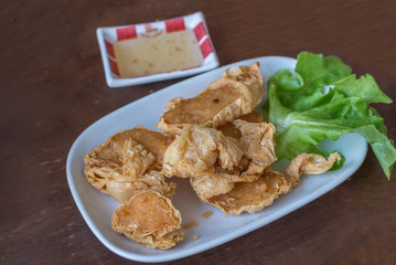 Deep fried crab meat rolls served on white plate on wooden table