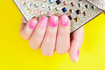 Hand with manicured nails covered with pink nail polish 