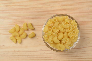 Pasta codos en un bol de cristal sobre fondo de madera