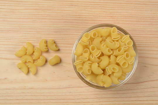 Pasta codos en un bol de cristal sobre fondo de madera