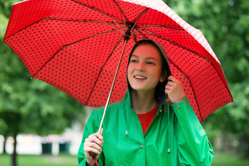 Young woman in raincoat holding umbrella