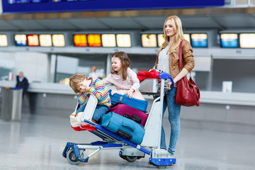 Little girl and boy and young mother with suitcases on airport