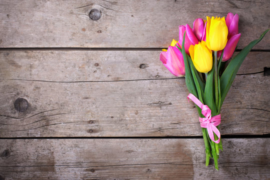 Bunch of bright yellow and pink spring tulips on vintage wooden