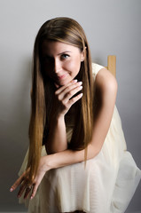 Beautiful woman wearing a dress sitting on a chair. Studio shot.