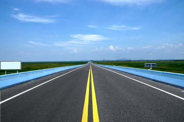 Empty road and the yellow traffic lines with blue sky.