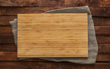 Cutting board on brown wooden table, top view