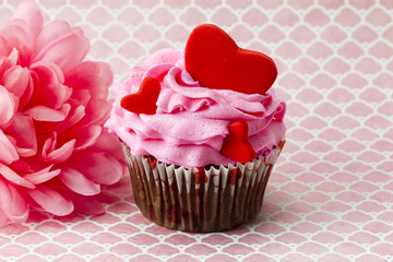 close-up image of strawberry cupcake with flower in background.