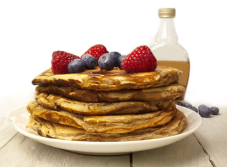 Stack of homemade pancackes with generic maple syrup bottle