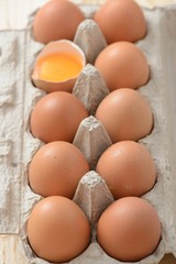 brown eggs in carton with an open egg