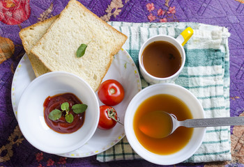 Tomatoes healthy soup with souce and bread slice and black tea