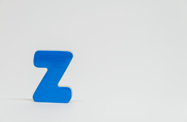 Blue wooden alphabet Z with white background and selective focus