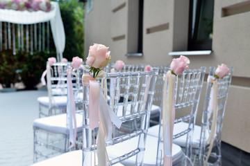 Beautiful wedding arch and chairs for marriage decorated with lace fabric and flowers. White decor for bride and groom. Colorful decoration for celebration. Beauty bridal interior
