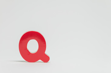 Red wooden alphabet Q with white background and selective focus