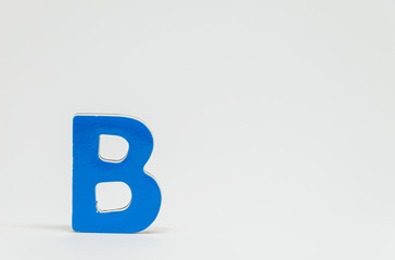 Blue wooden alphabet B with white background and selective focus